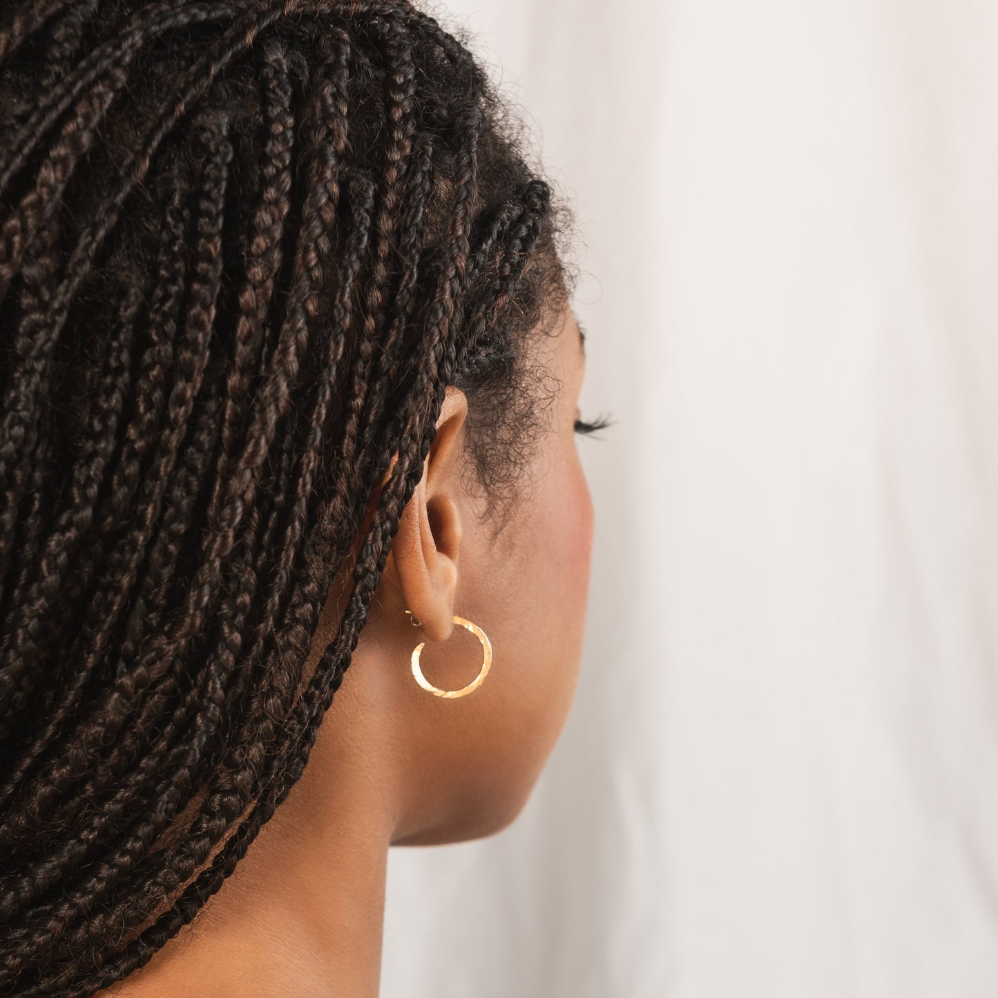 small hammered gold hoop earring being worn by model