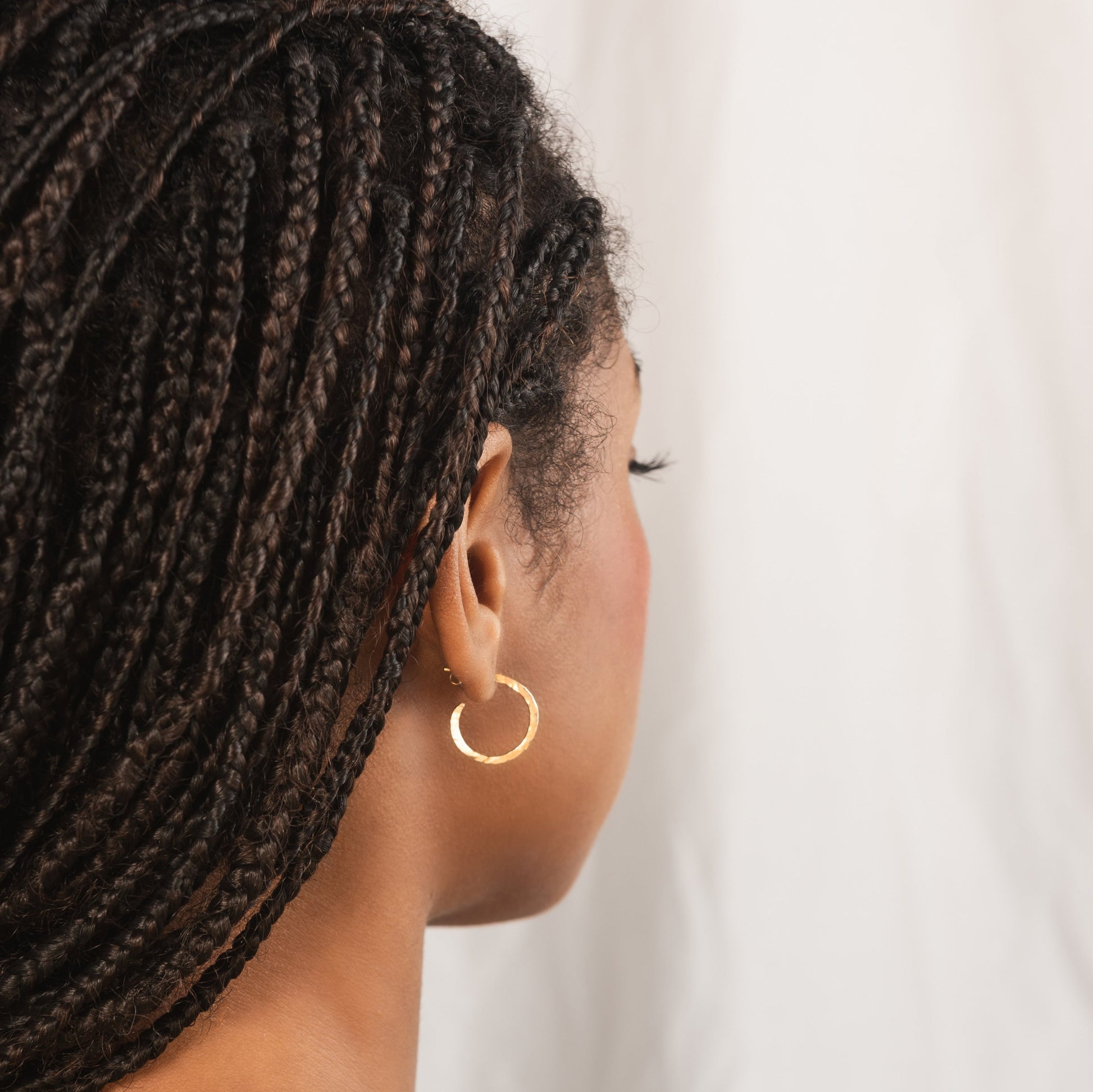 small hammered gold hoop earring being worn by model