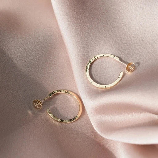 9ct gold hoop earrings laying on a pale pink silk background