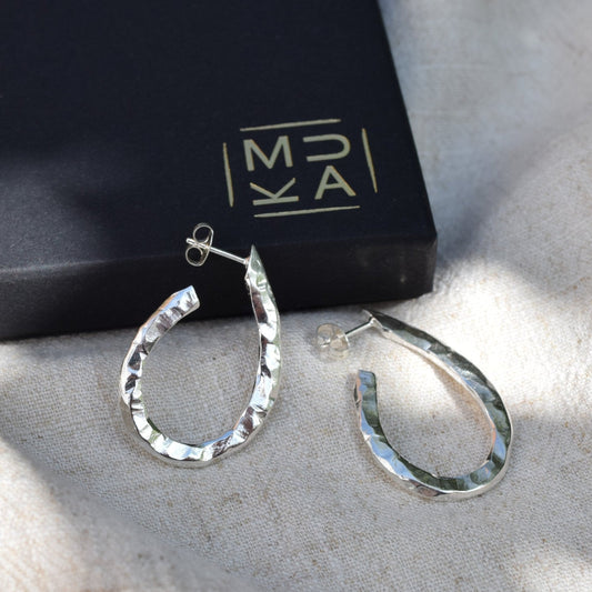 Image of carvel oval hoop earrings in silver sitting next to MUKA gift box