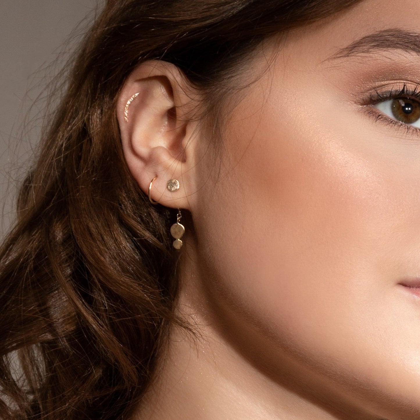 Model wears 9ct gold hammered helix stud paired with gold Ella earrings