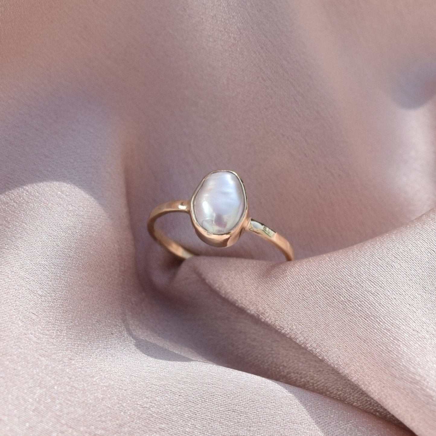 9ct gold pearl ring laying on silk fabric