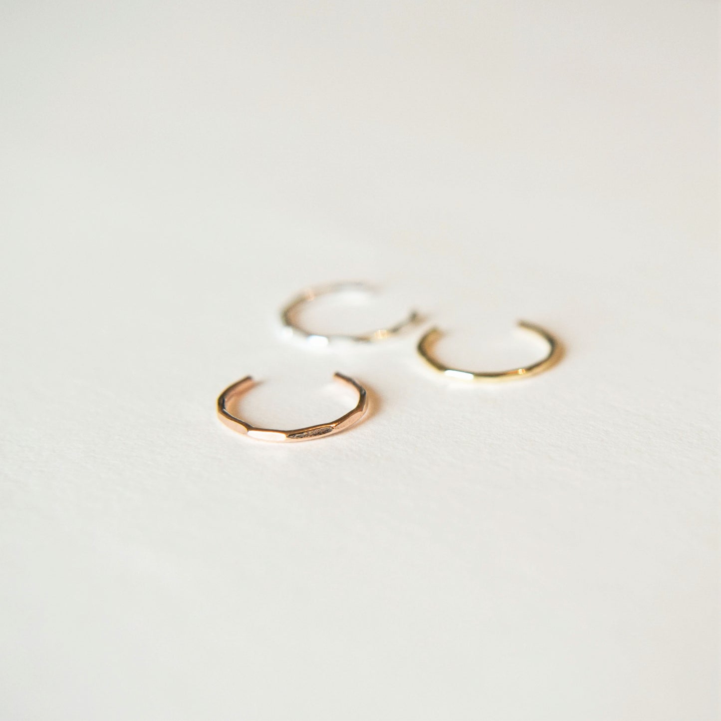 three conch cuffs; silver, gold and rose gold laying on white background