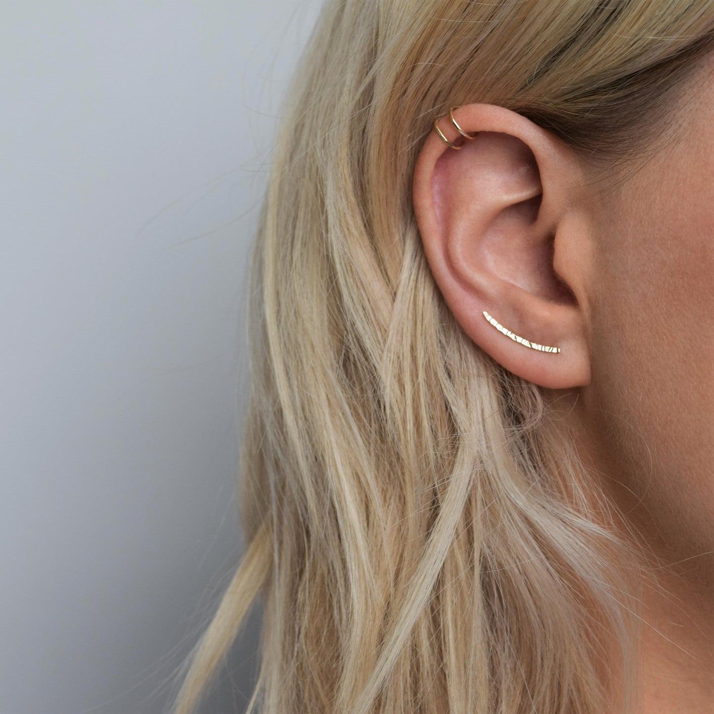 Gold double helix cuff worn alongside gold ear climbers