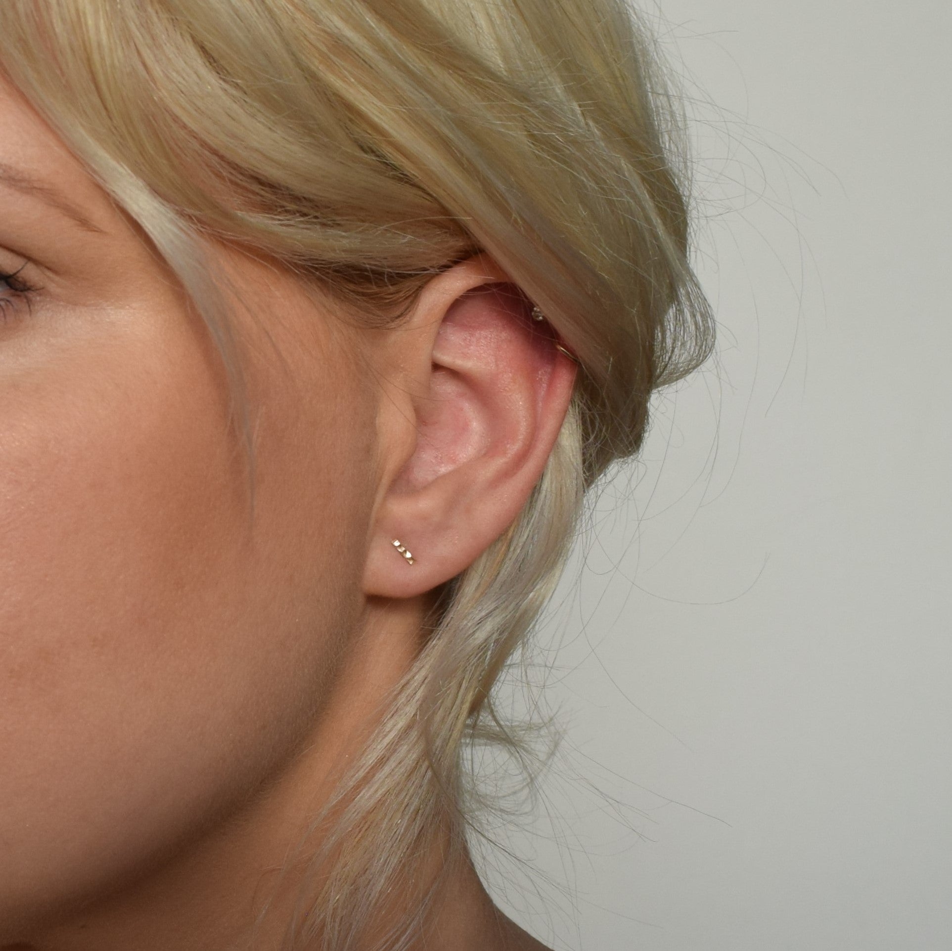 gold hammered bar studs worn by blond model