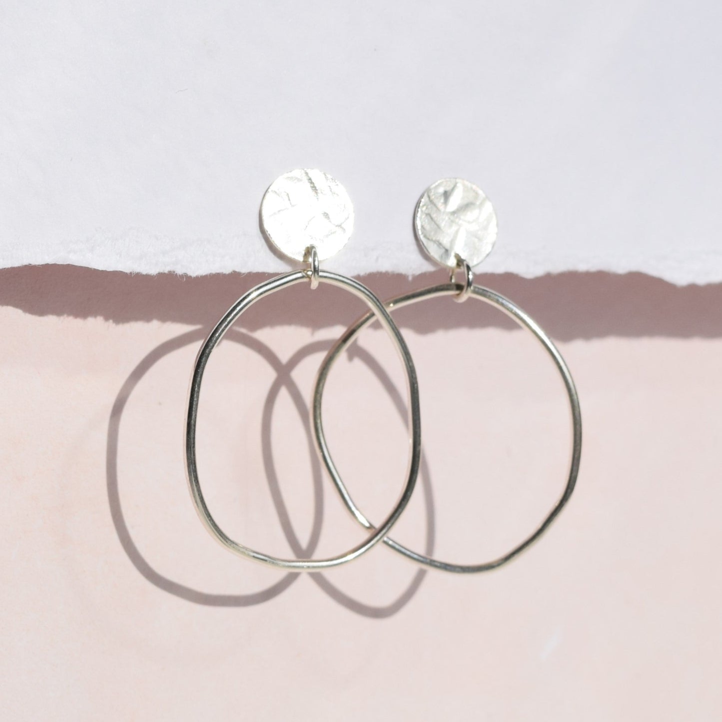 Clara earrings handing from card with pink background