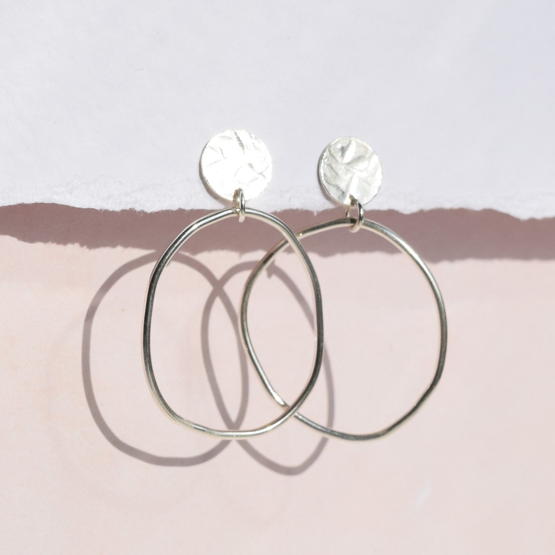 Clara earrings handing from card with pink background