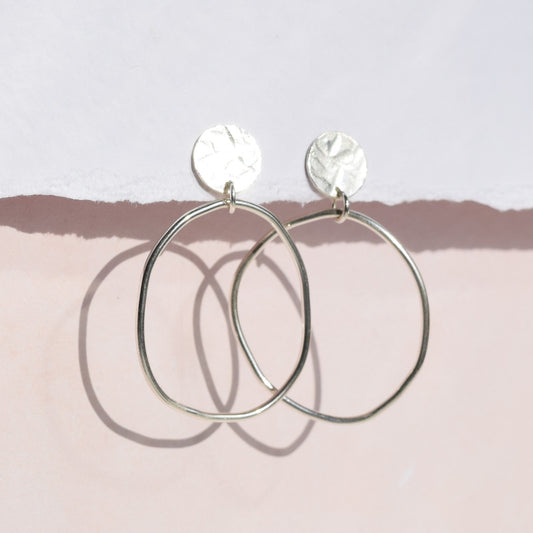 Clara earrings handing from card with pink background