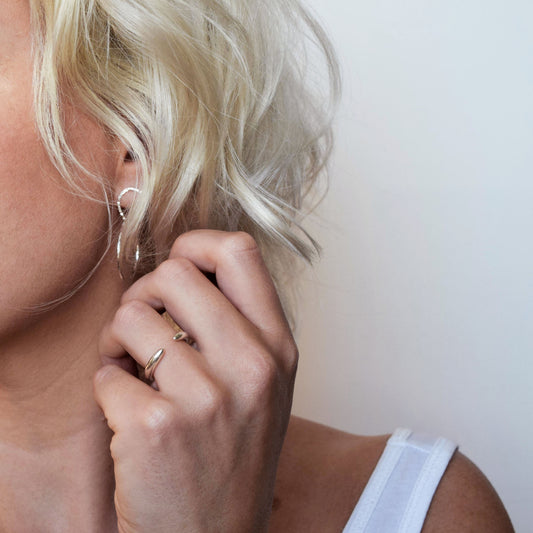 Silver cuff ring worn on ring finger by blond model