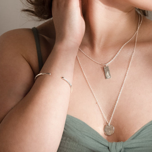 Molten cuff bangle worn alongside two silver necklaces