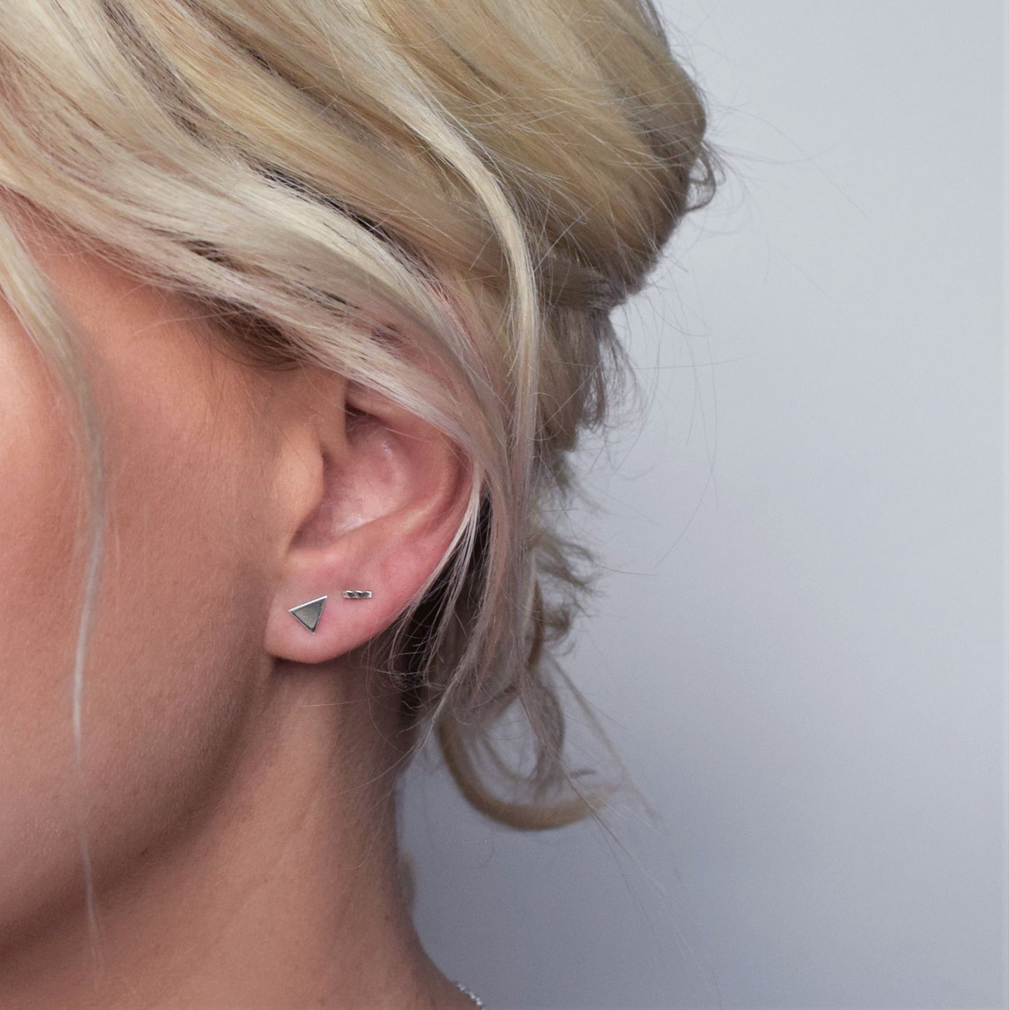 Silver solid triangle studs worn with hammered bar stud