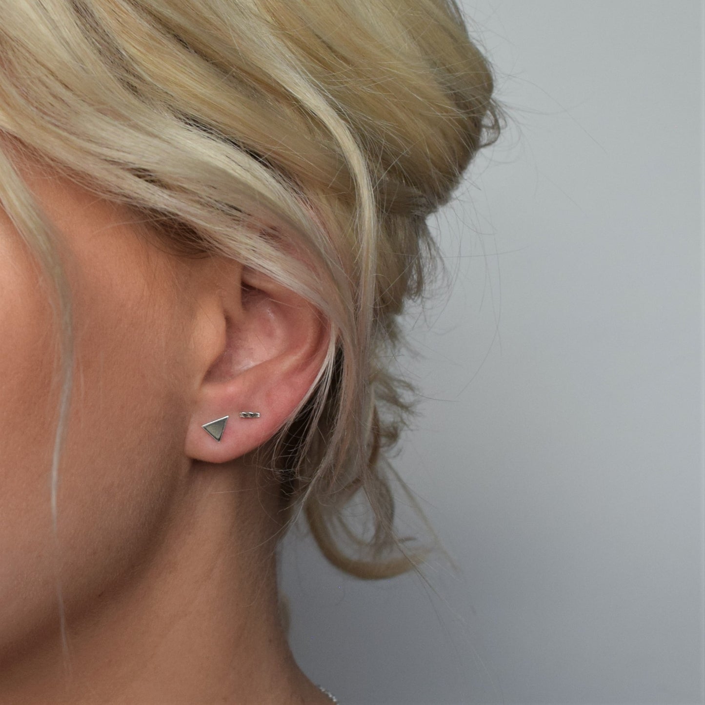 silver hammered bar stud worn alongside solid triangle studs
