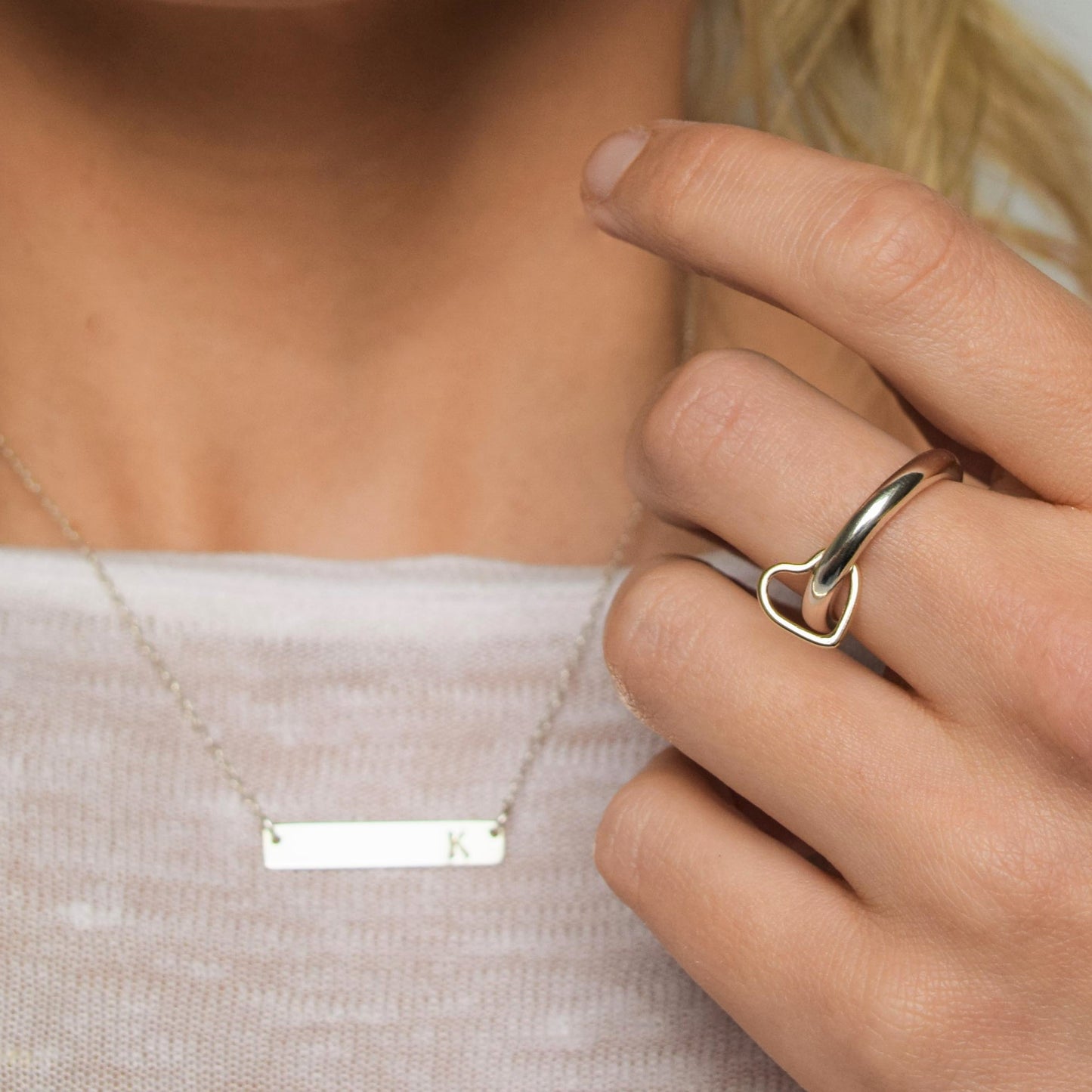 Silver worry spinner ring with solid gold spinner modelled next to bar necklace personalised with initial K