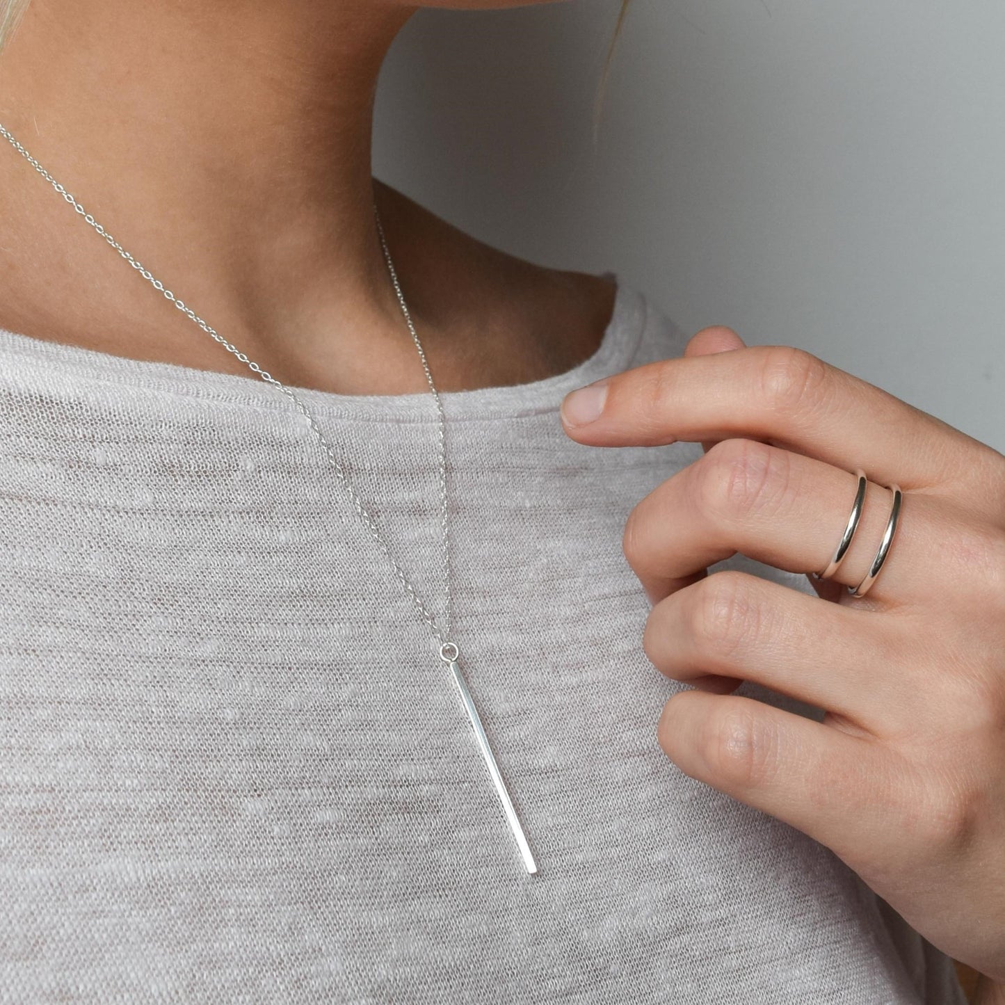 vertical bar necklace worn alongside cage ring