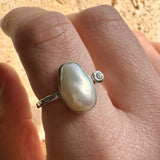 Silver ring with a large pearl on a person's finger