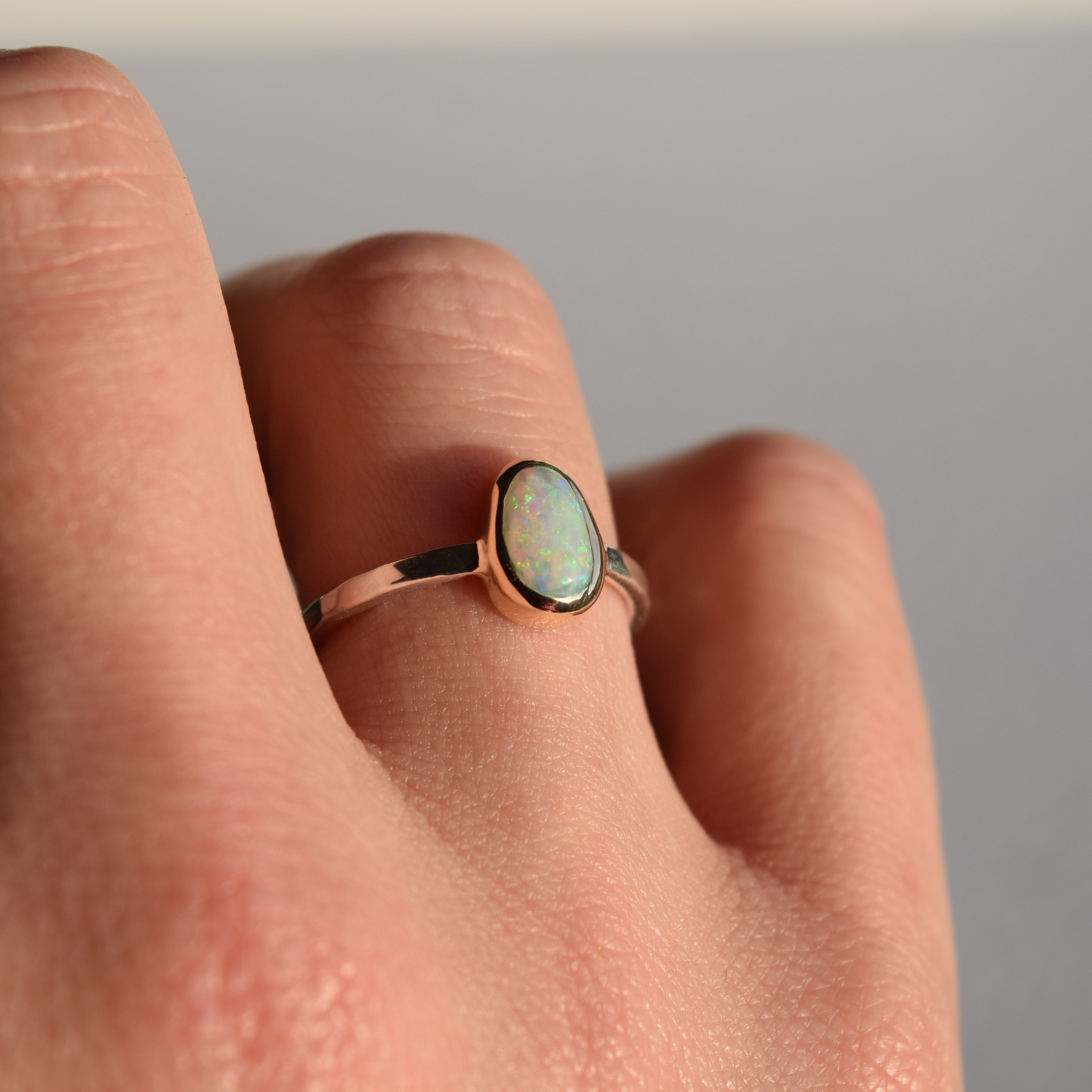 Ring with a green gemstone on a person's finger against a neutral background