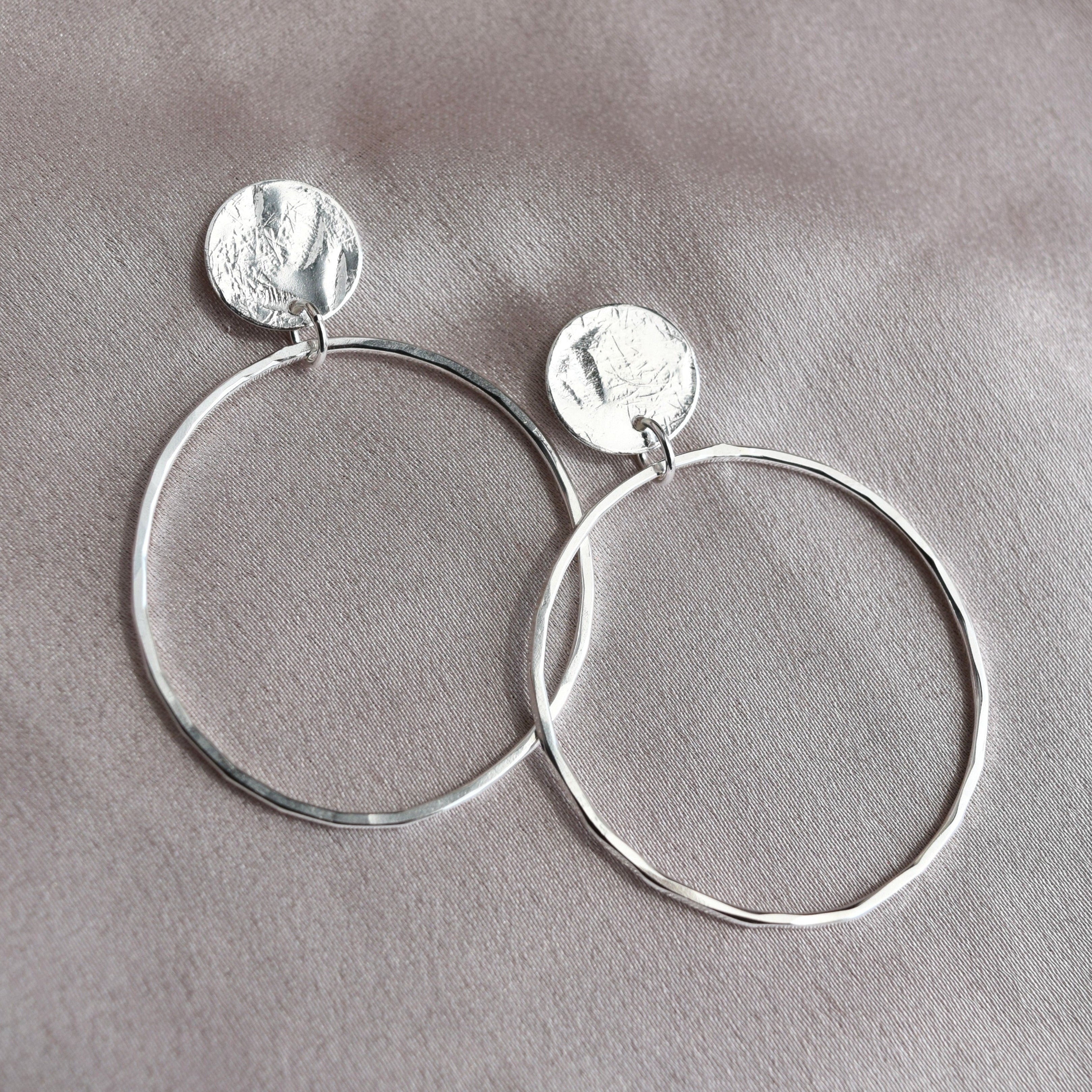 Hammered silver drop earrings made up of circles and ovals. Beaten texture and free moving open circle design, delicate and handmade in Scotland
