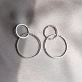 A pair of minimalist silver hoop earrings with light hammered finish created in recycled sterling silver