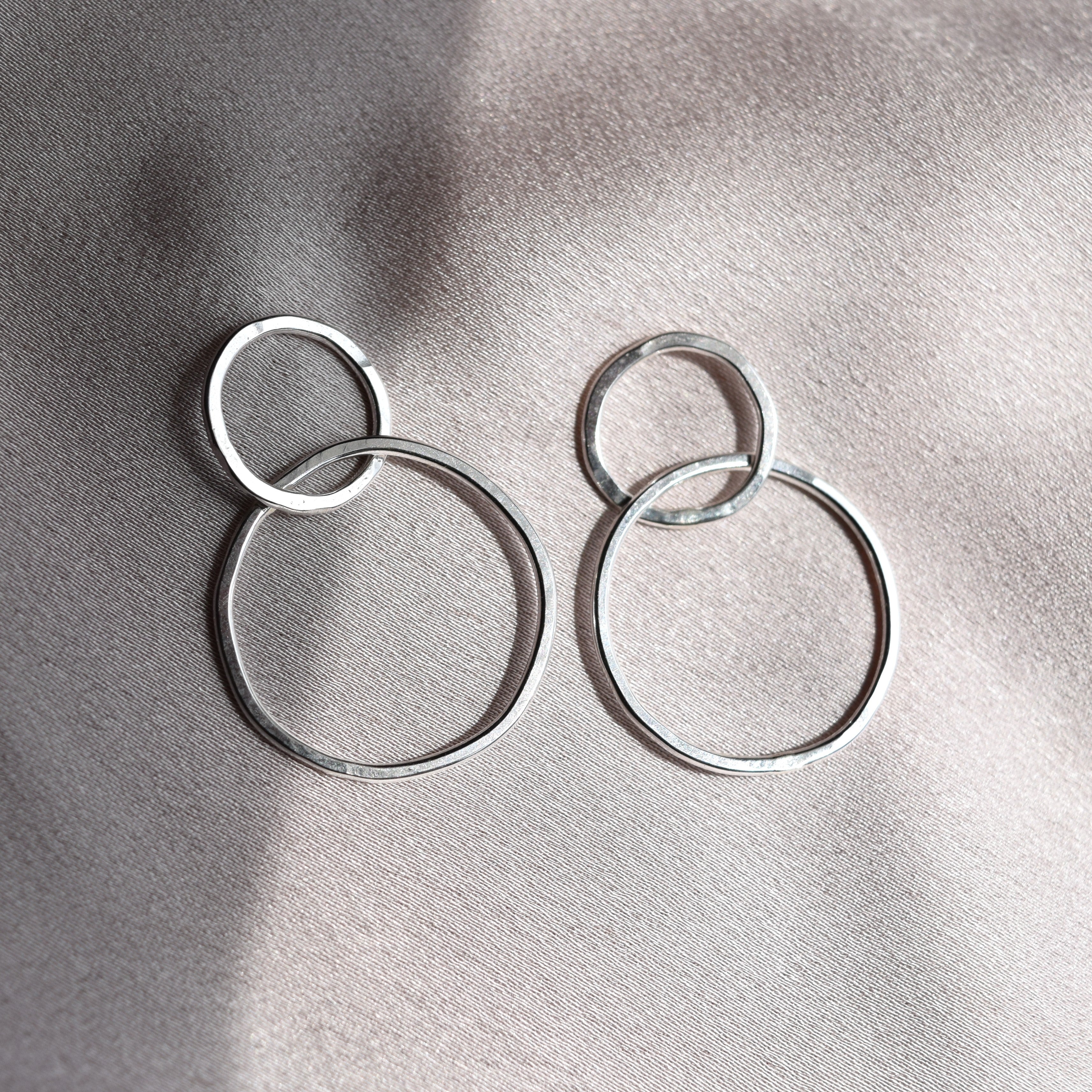 A pair of minimalist silver hoop earrings with light hammered finish created in recycled sterling silver
