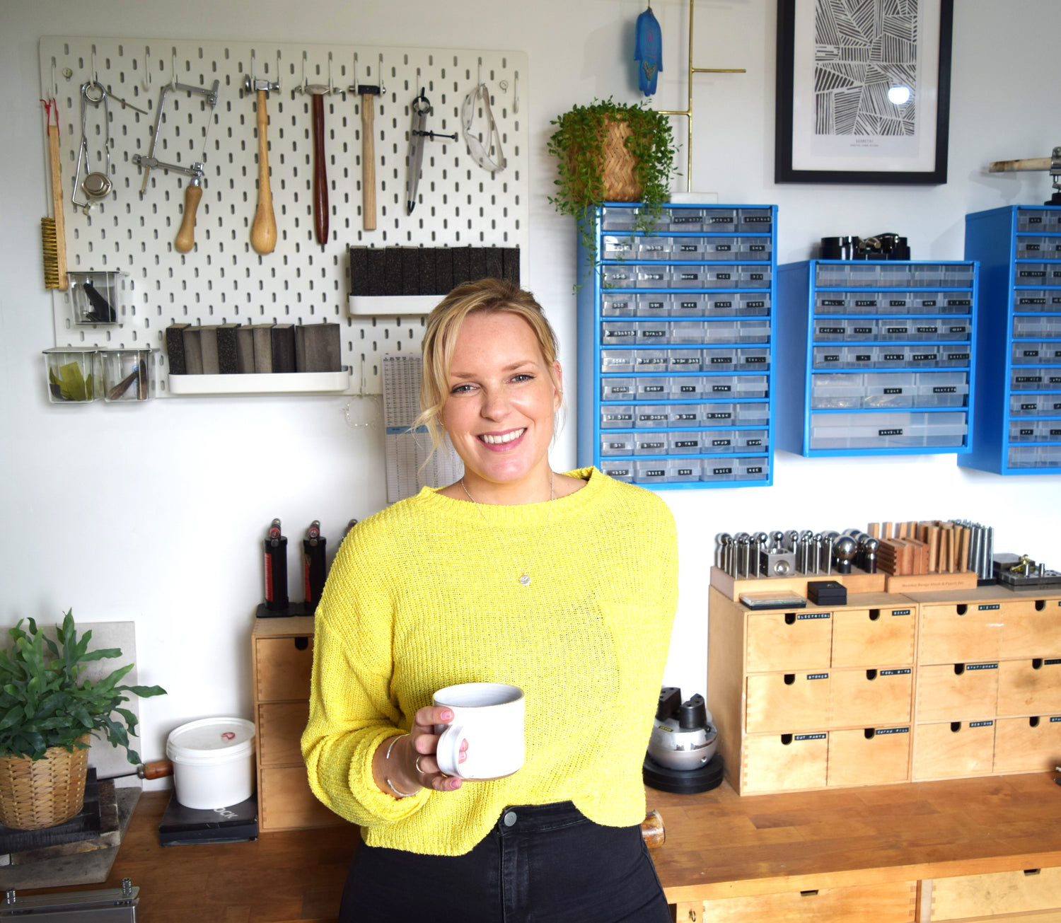 Image of silversmith Claire Maleham standing in her studio with equipment behind her