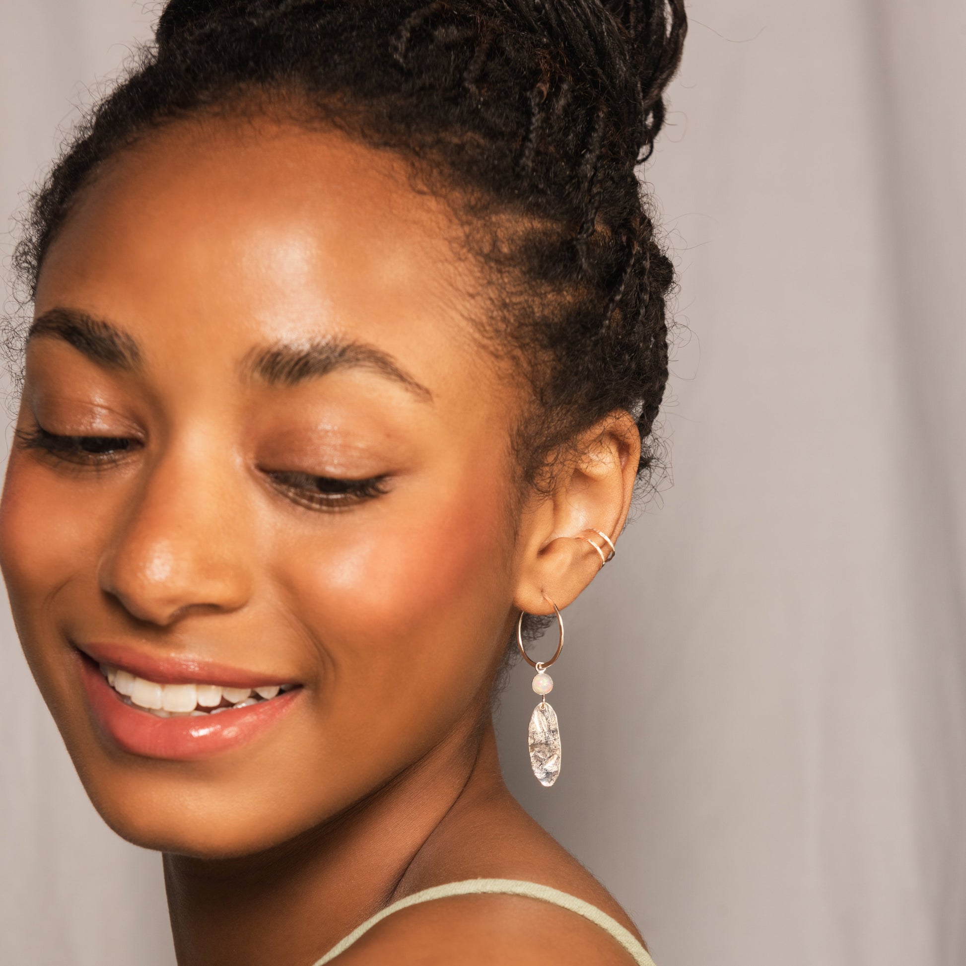 Model wearing silver drop earring alongside silver double conch cuff