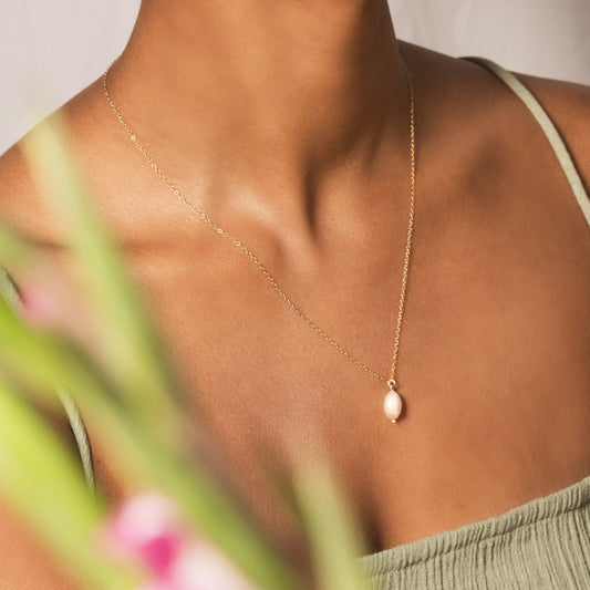 model wearing gold pearl necklace and pearl hoop earrings