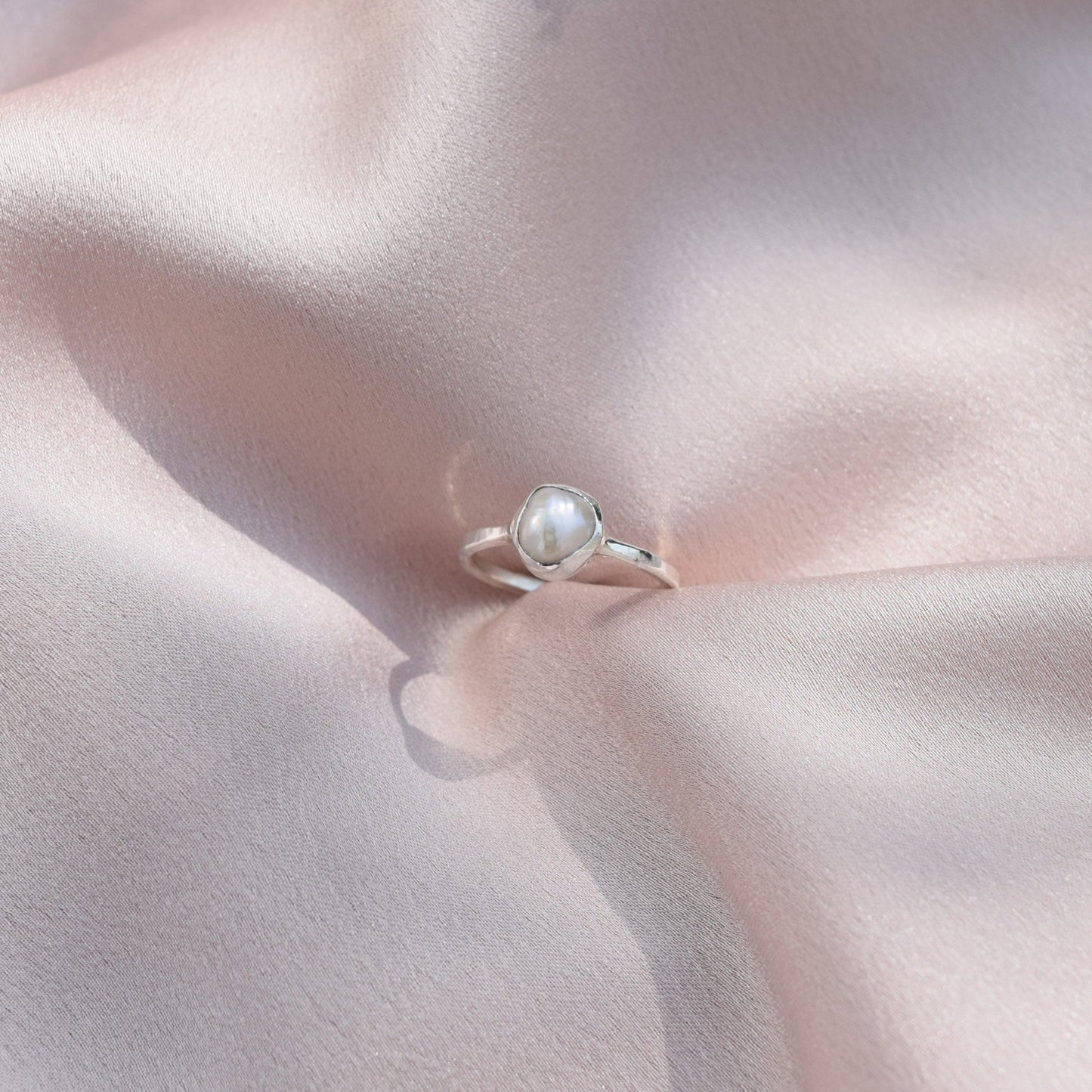 silver pearl ring sitting on silk fabric