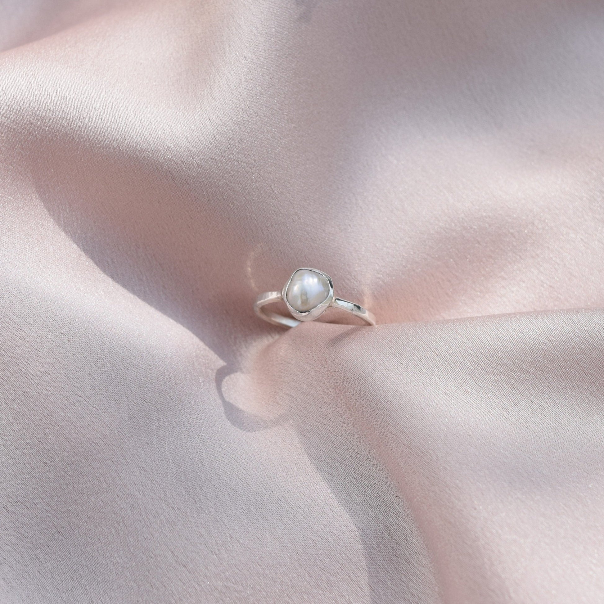 silver pearl ring sitting on silk fabric