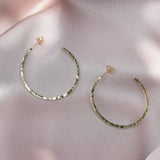 solid 9ct gold hoop earrings laying on a blush pink fabric background