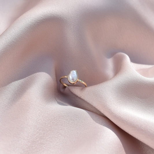 9ct gold pearl ring laying on silk fabric