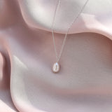 silver pearl necklace laying on silk fabric