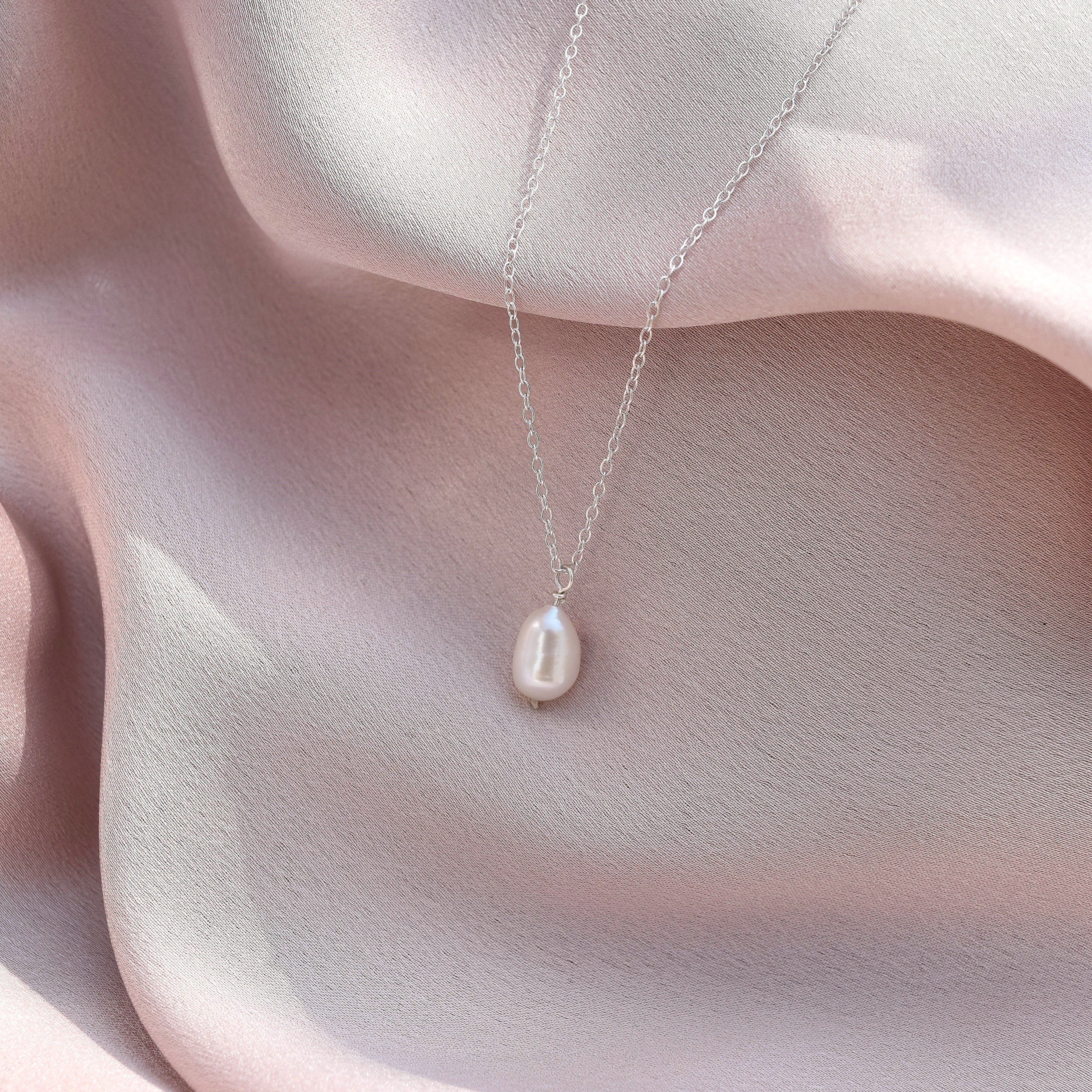silver pearl necklace laying on silk fabric