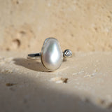 Pearl ring with a diamond on a sandy background