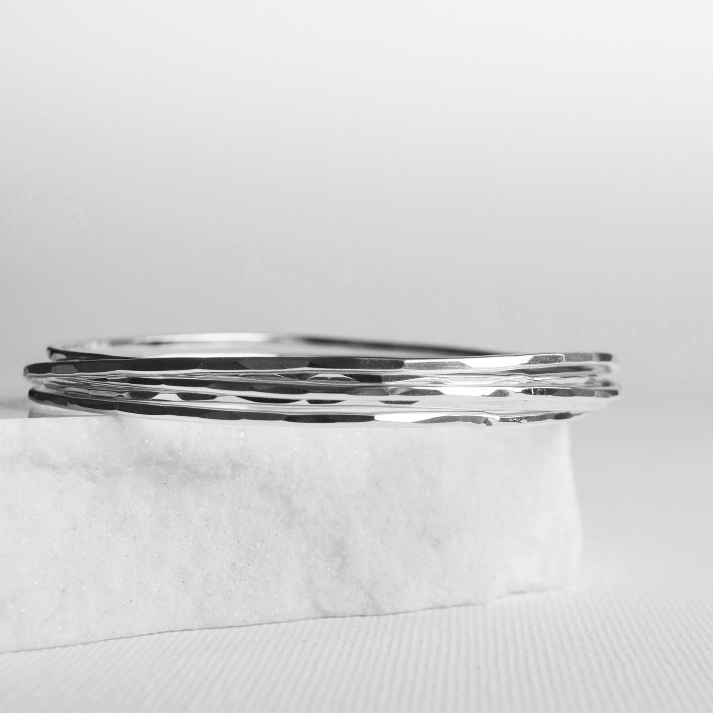 Recycled silver stacking bangles with hammered finish on white background