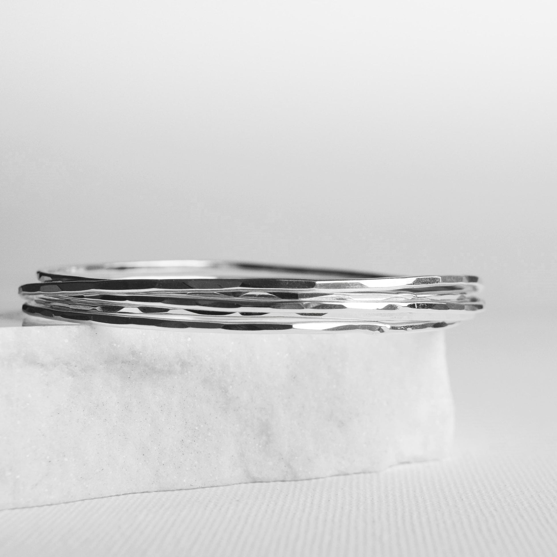 Recycled silver stacking bangles with hammered finish on white background