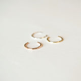 three conch cuffs; silver, gold and rose gold laying on white background
