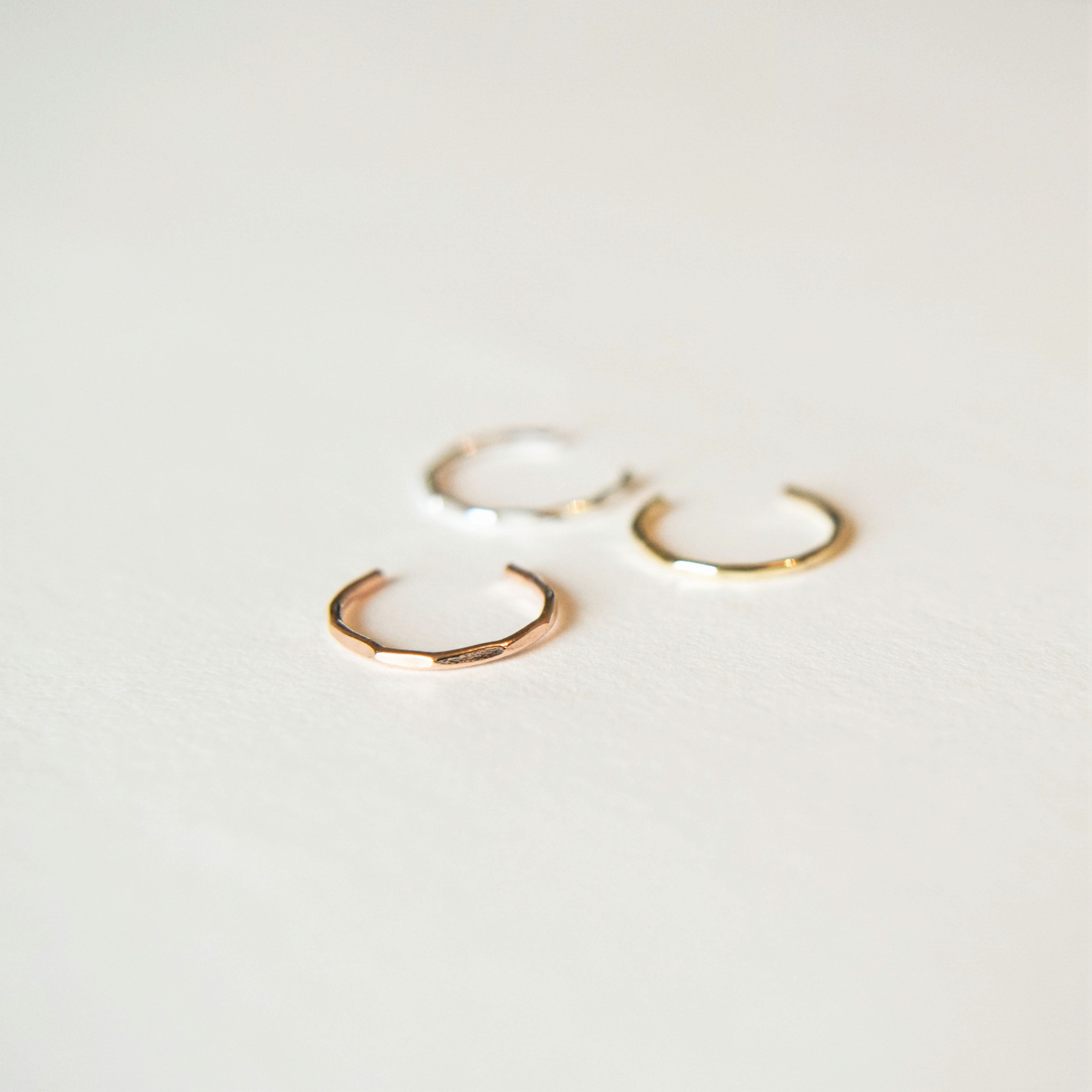 three conch cuffs; silver, gold and rose gold laying on white background
