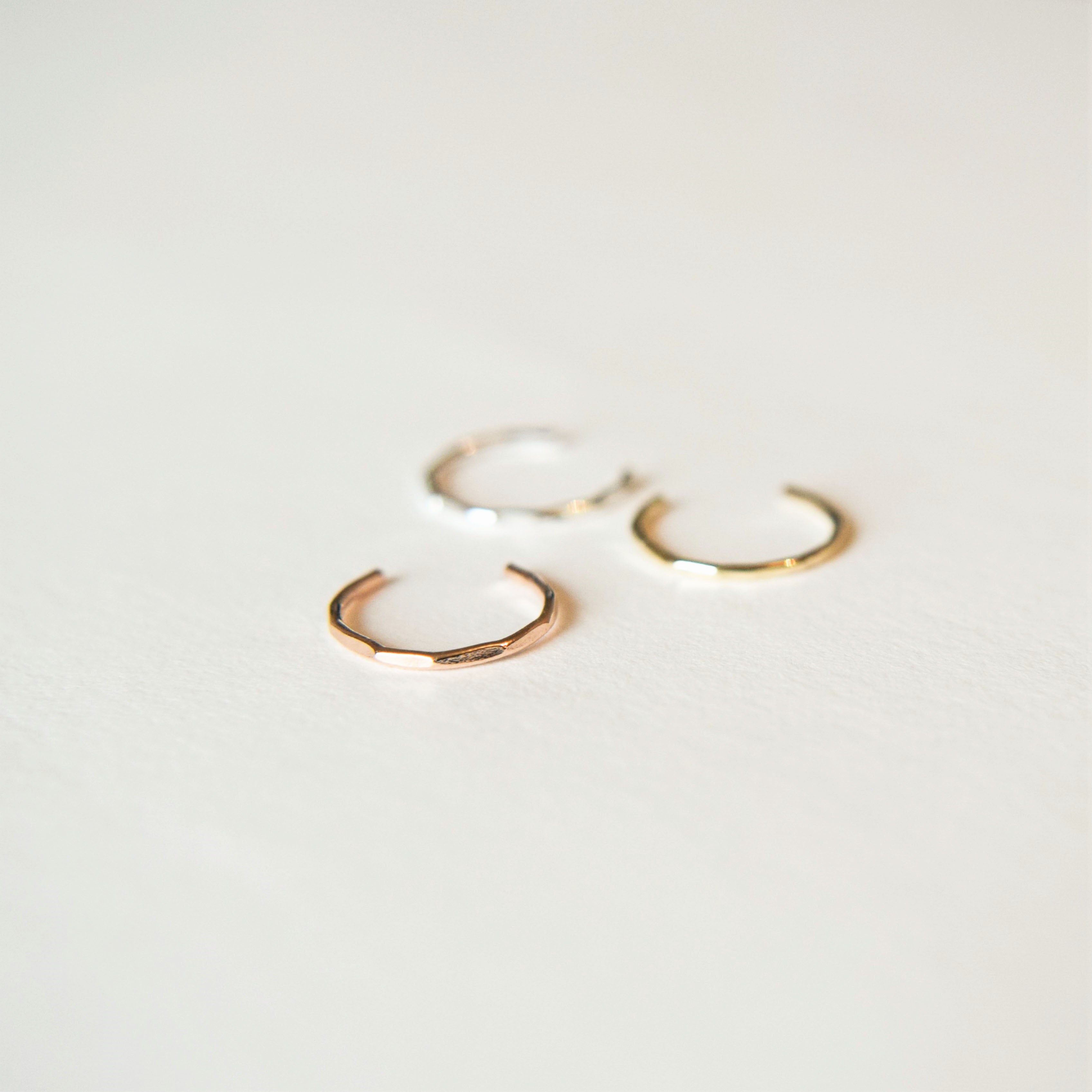 three conch cuffs; silver, gold and rose gold laying on white background