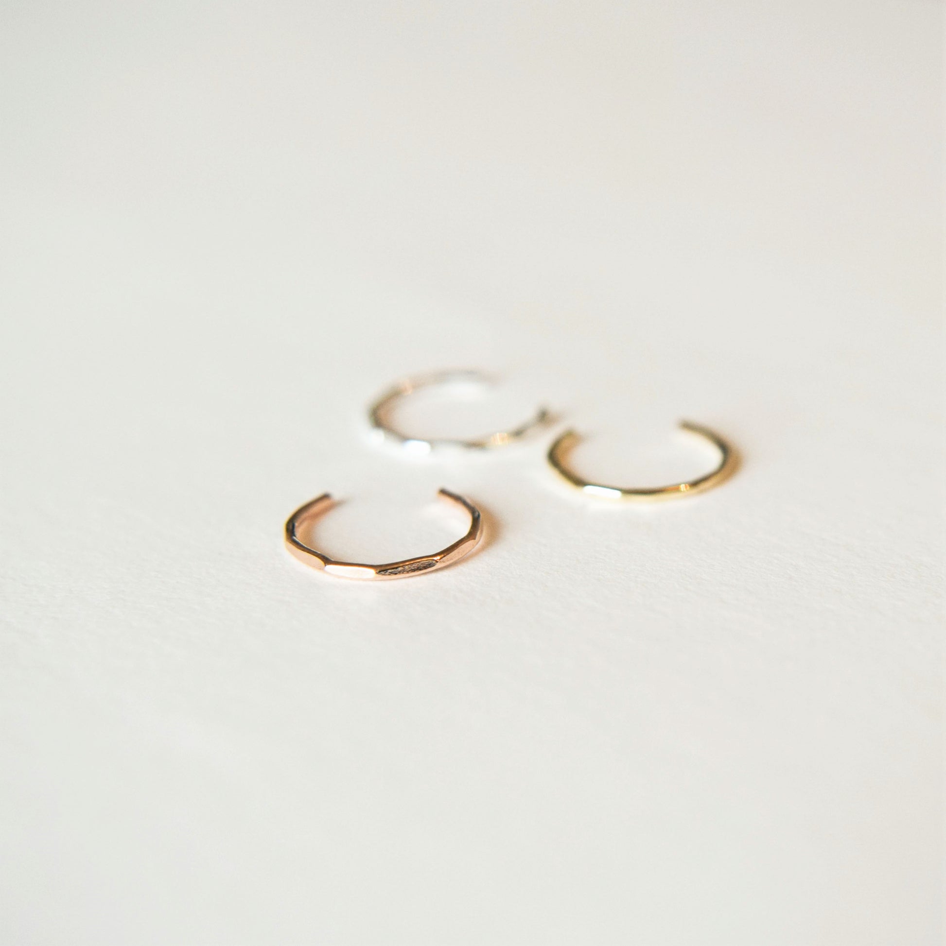 three conch cuffs; silver, gold and rose gold laying on white background