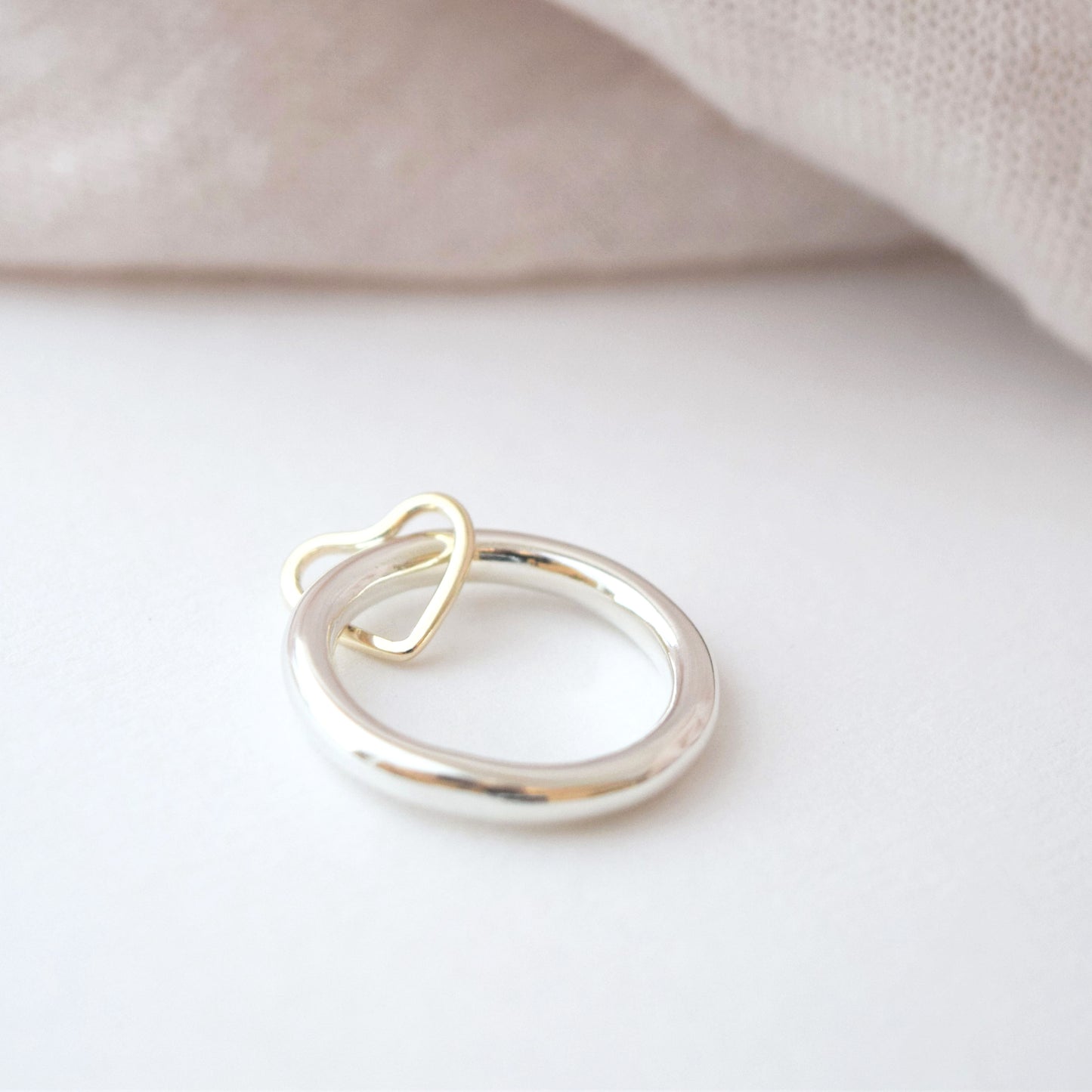 Heart spinner ring on white background with pale pink fabric