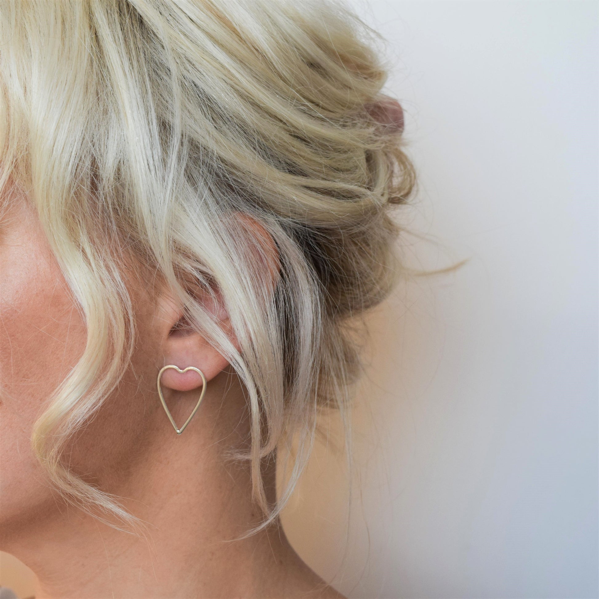 Open heart earrings worn by blond haired model