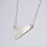 MUKA studio triangle necklace close up showing textured finish on silver pendant