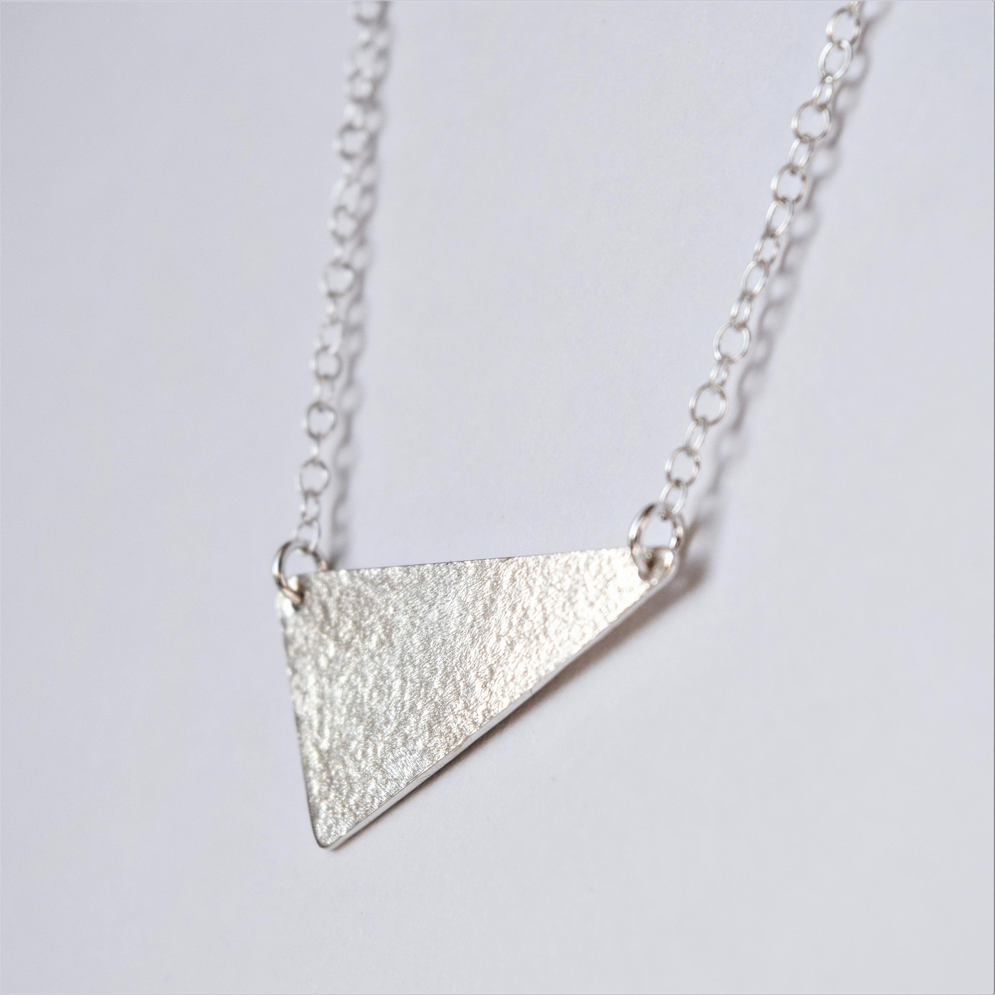 MUKA studio triangle necklace close up showing textured finish on silver pendant