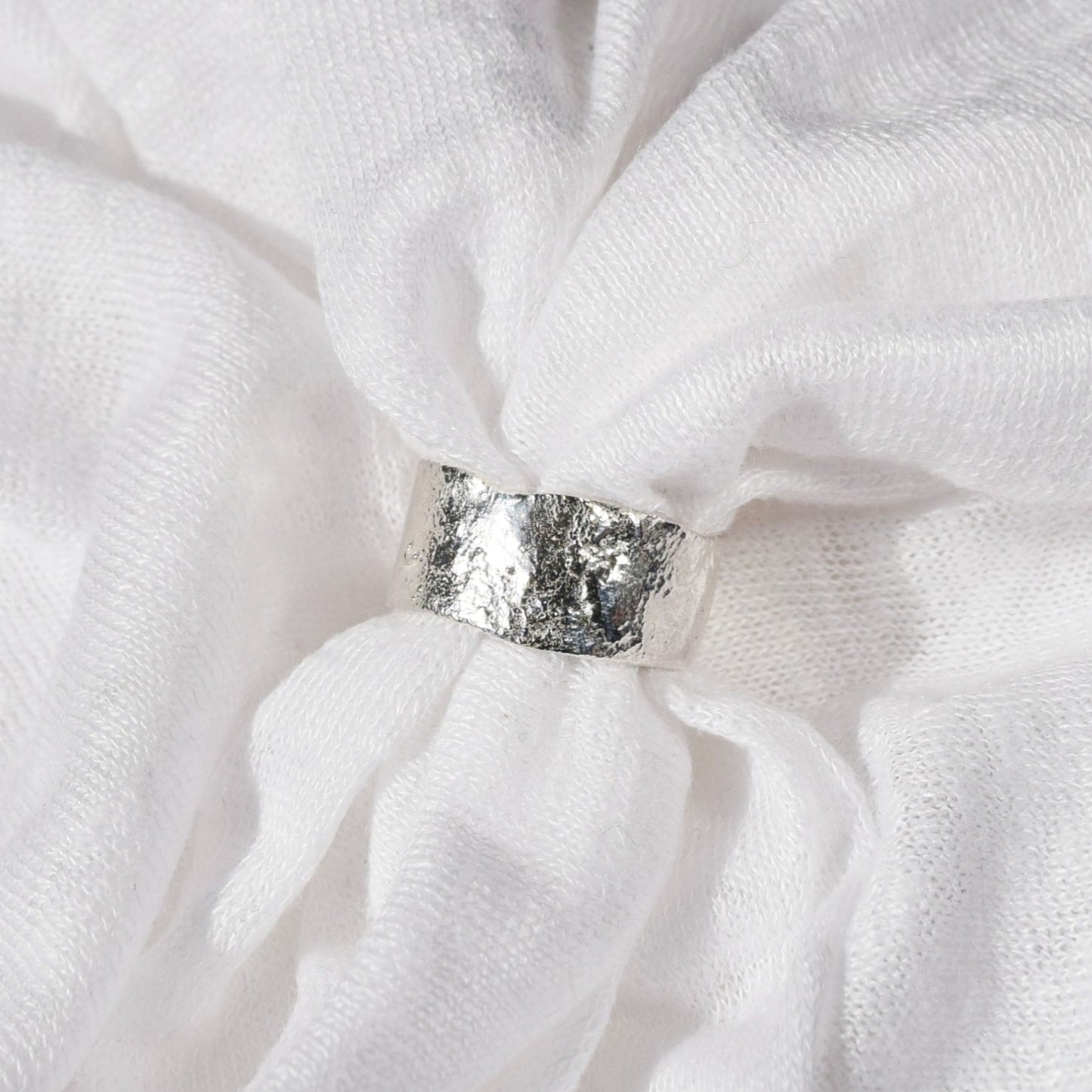 wide molten band ring placed within white fabric