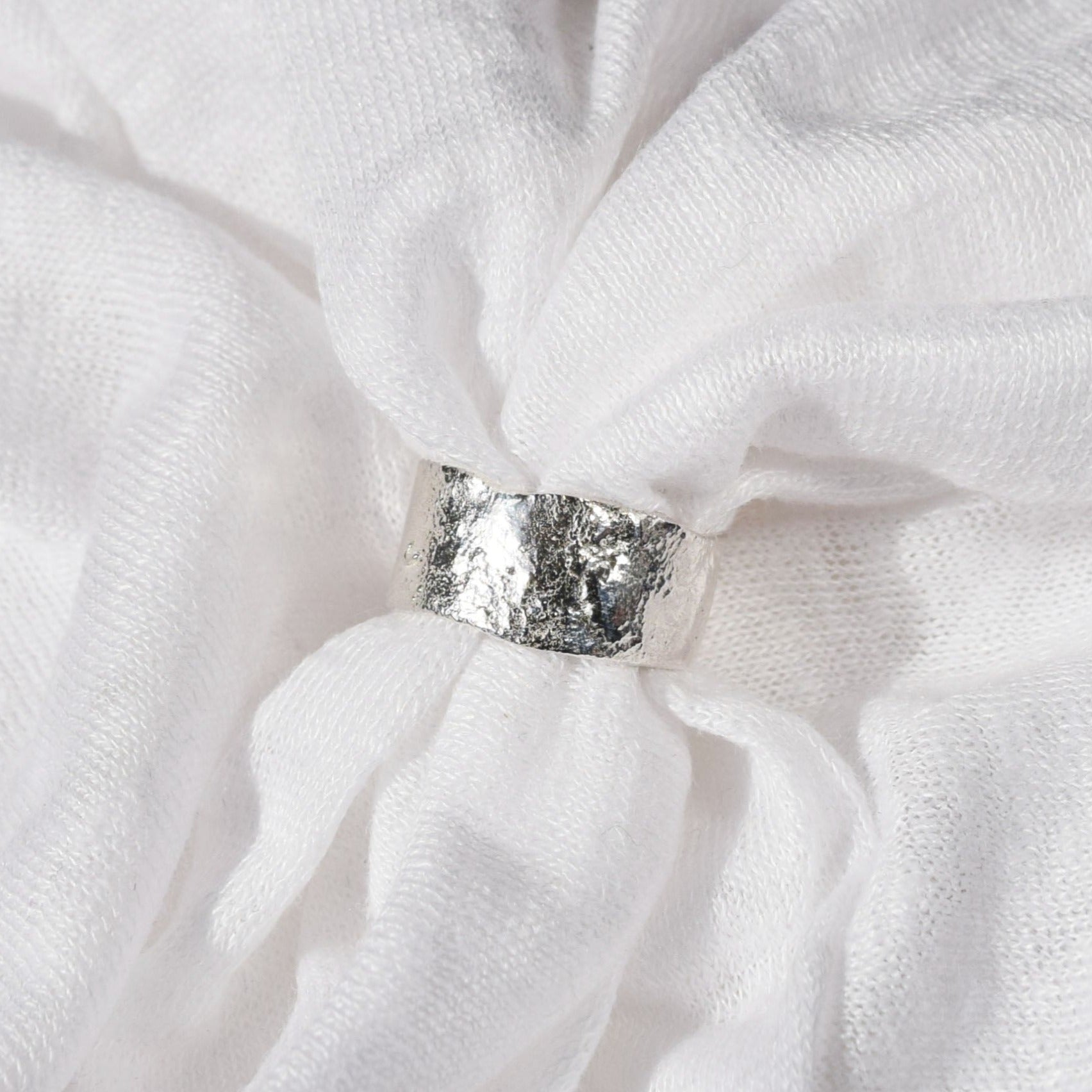 wide molten band ring placed within white fabric