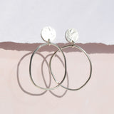Clara earrings handing from card with pink background