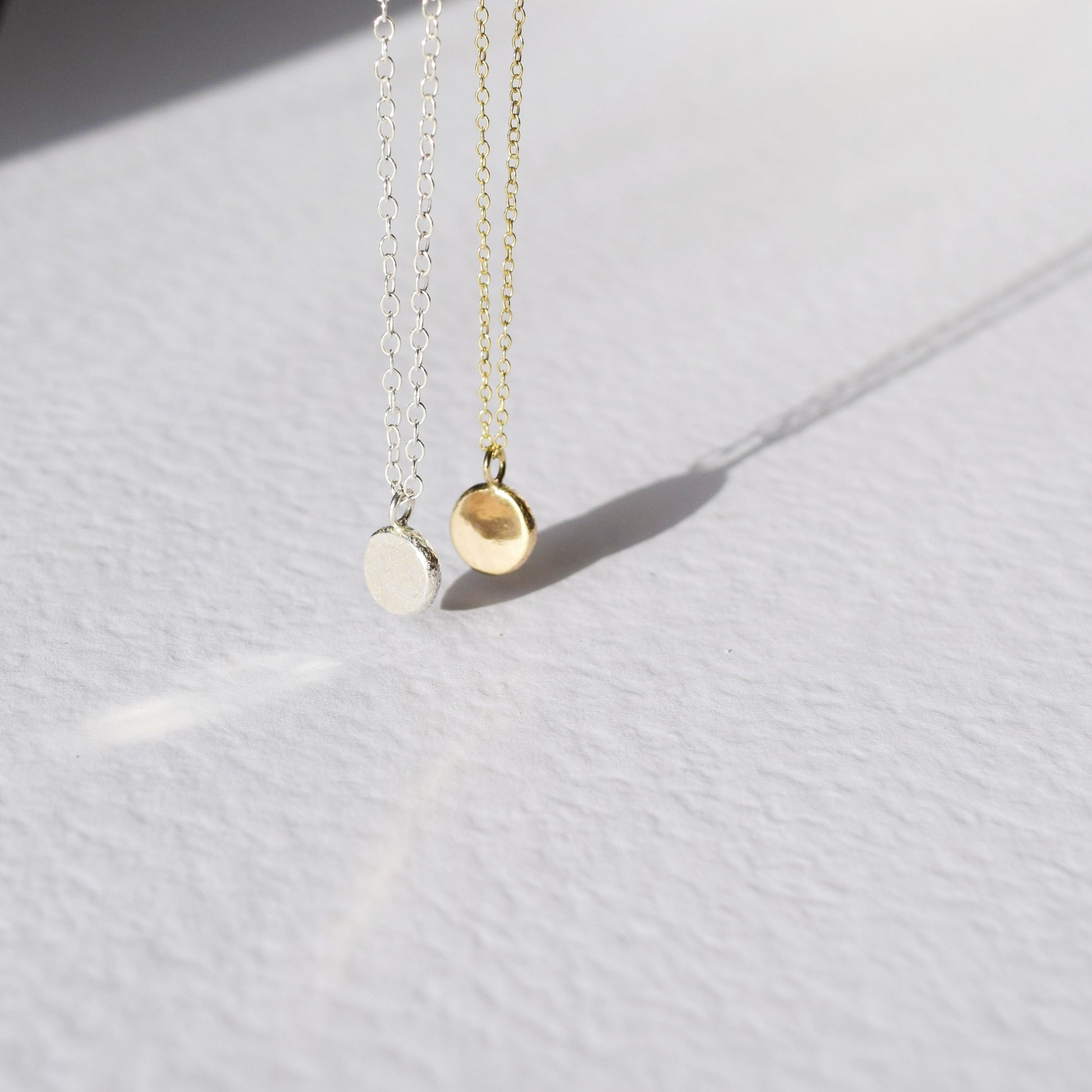 Gold and silver dot necklaces hanging in the sunlight