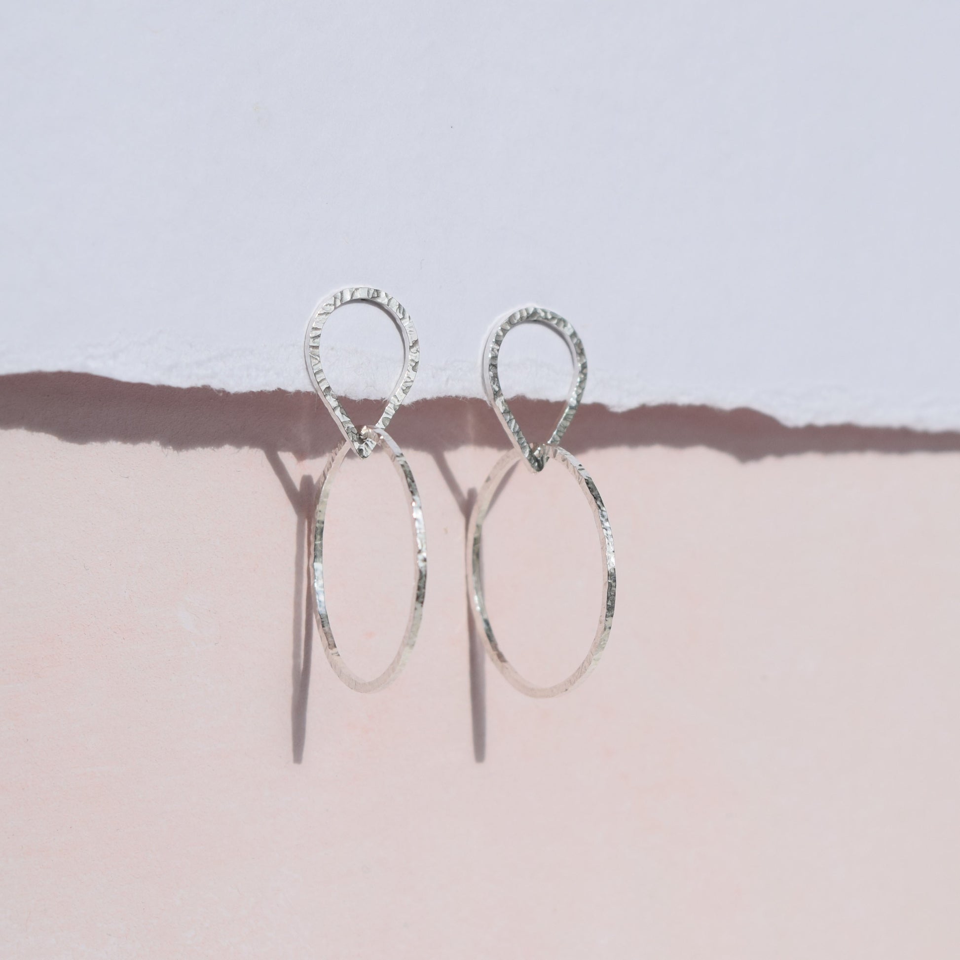 Teardrop circle earrings on pink and white background