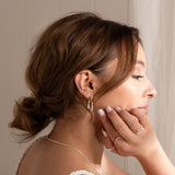 brown haired model wearing hand carved hoops, and three other earrings