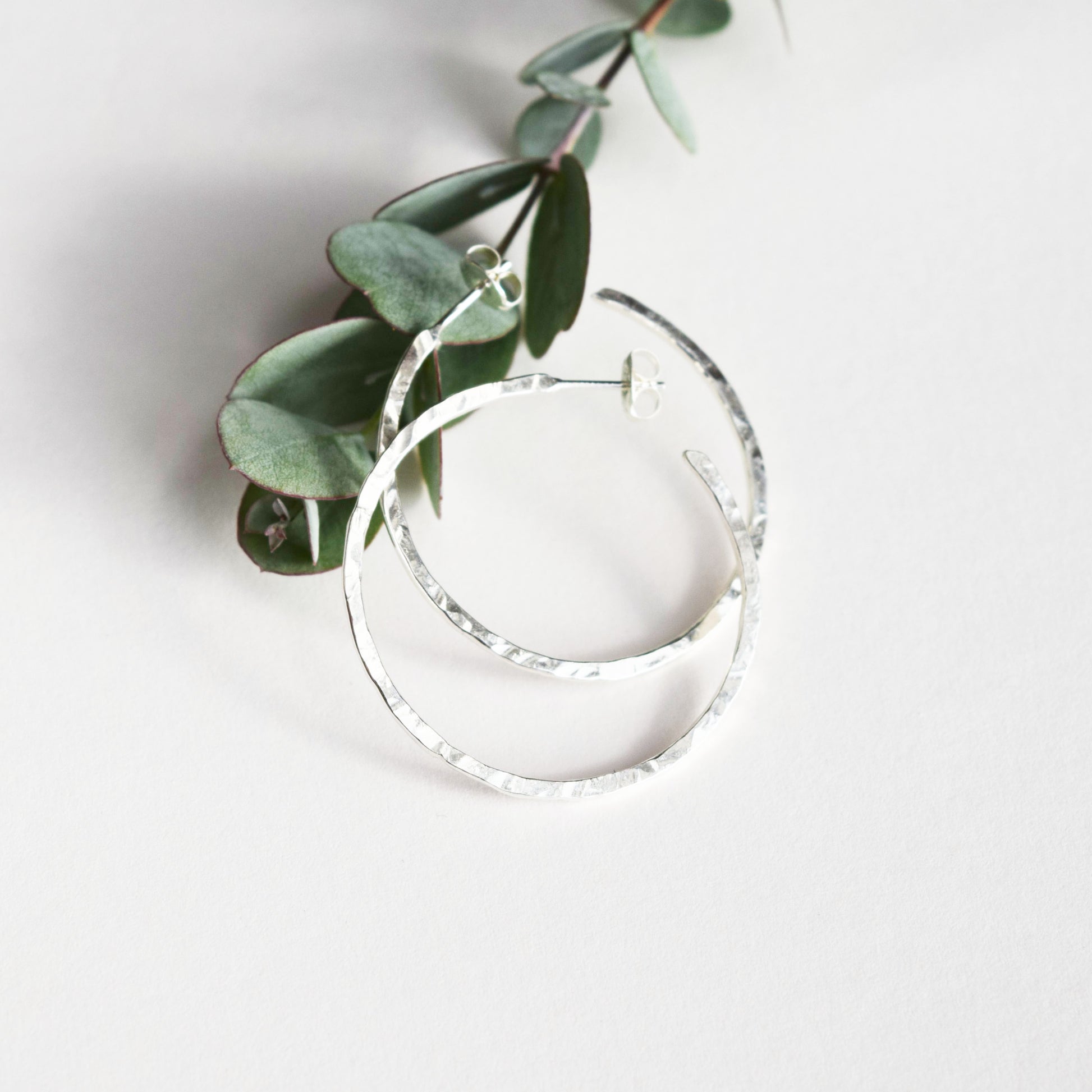 Mid sized hoop earrings on white background showing hammered finish